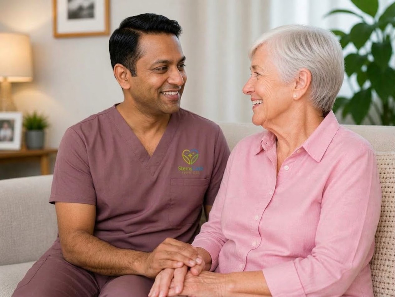 A StemsCare support worker holding hands with an older participant on the couch